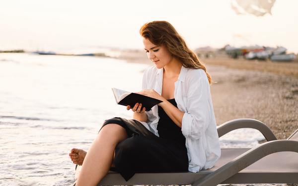 Frau liest die Bibel am Strand
